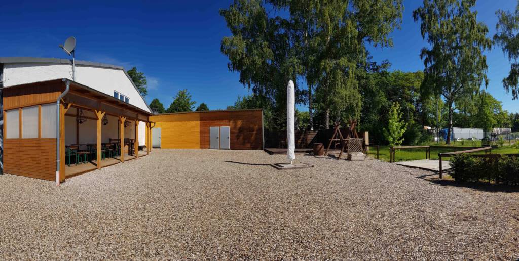 Weitläufige Außenfläche bei Leo’s Veranstaltungsräumen in Salzgitter mit Bäumen und Sitzmöglichkeiten im Hintergrund.