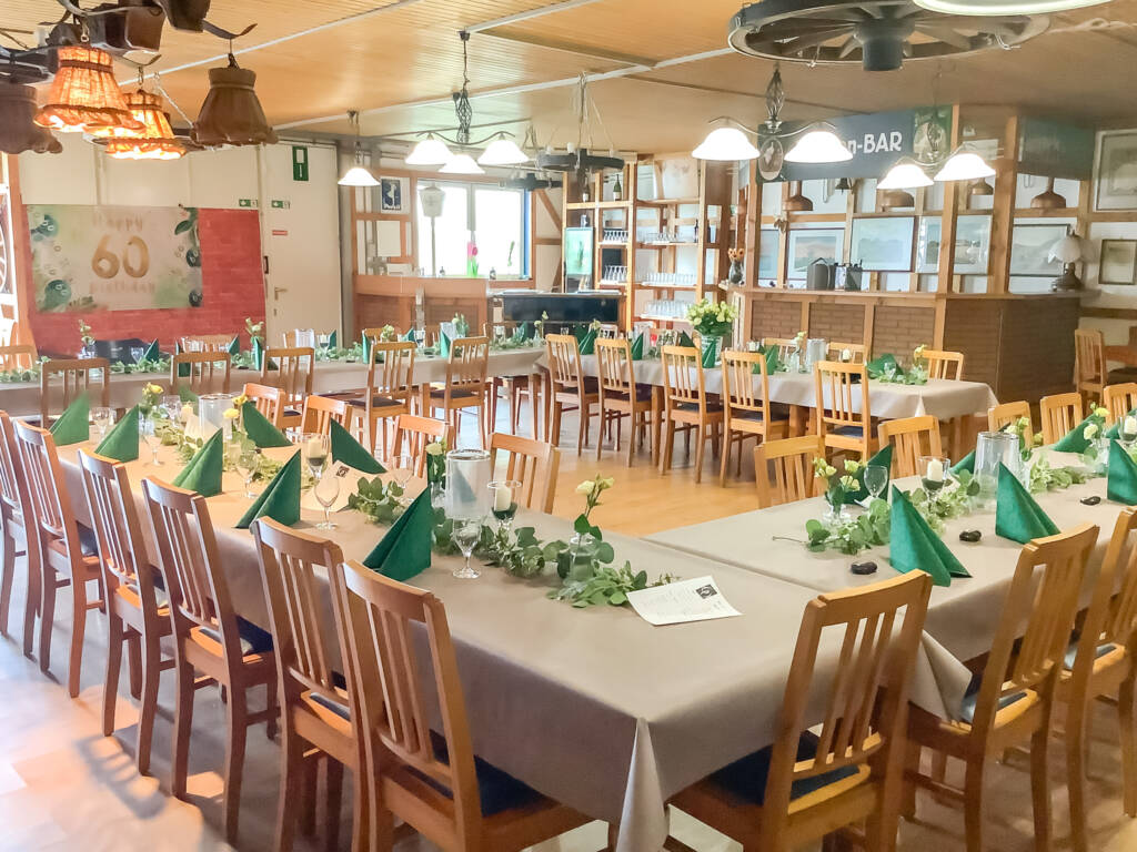 Festlich gedeckter Saal mit grüner Tischdeko für Partys