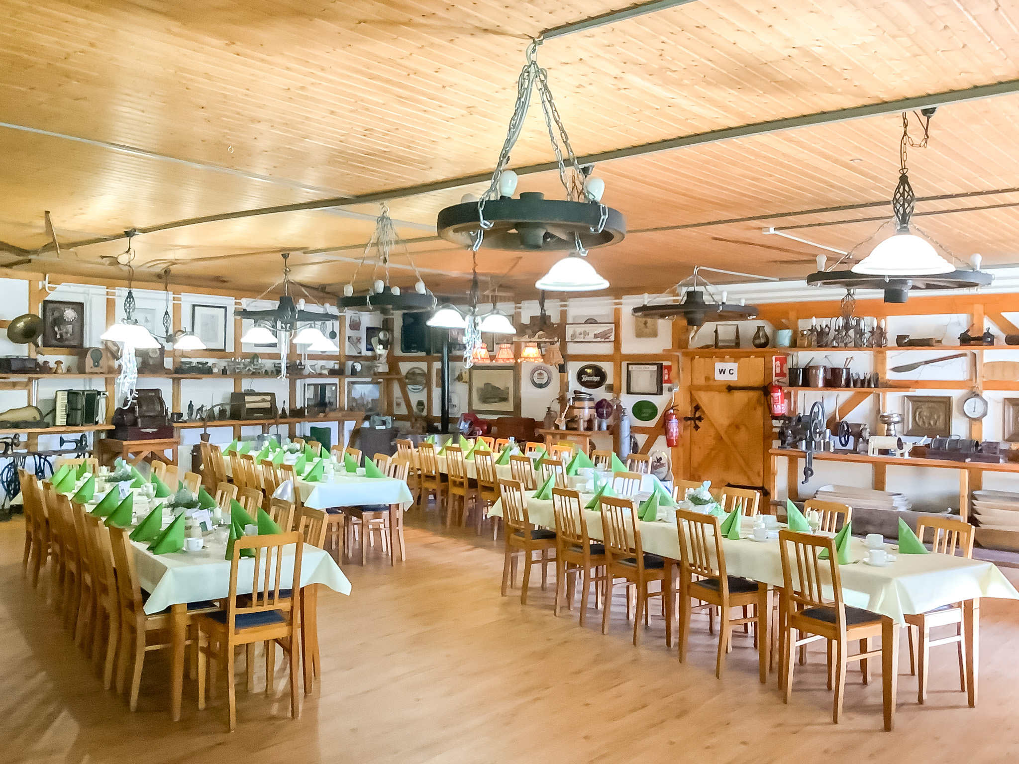 Große Eventlocation mit langen Tafeln in warmem Ambiente – ideal für Feiern und Veranstaltungen.