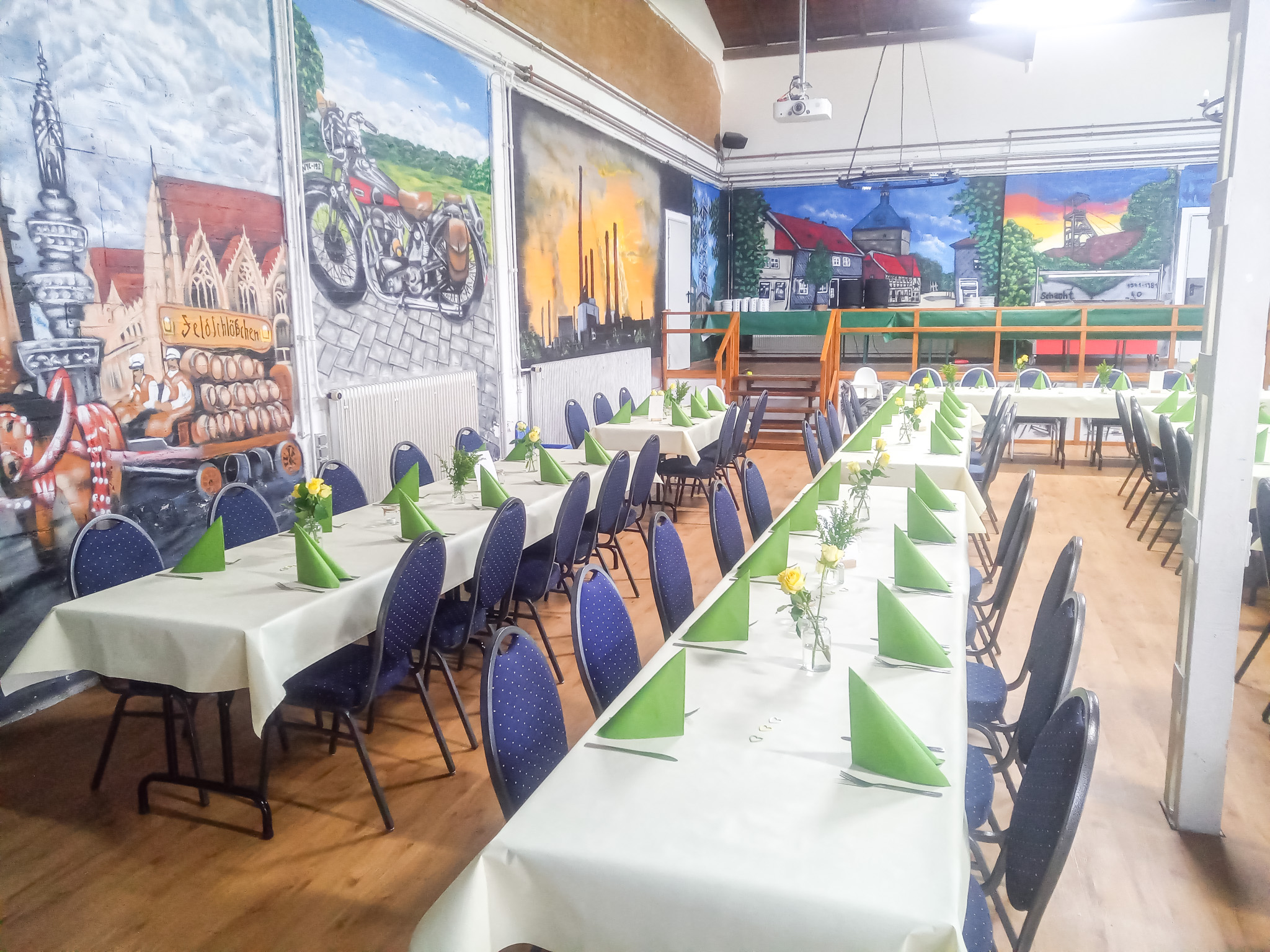 Festlich gedeckte Tische mit grüner Dekoration in der Meisterhalle, ideal für Hochzeiten, Jubiläen und Vereinsfeste.