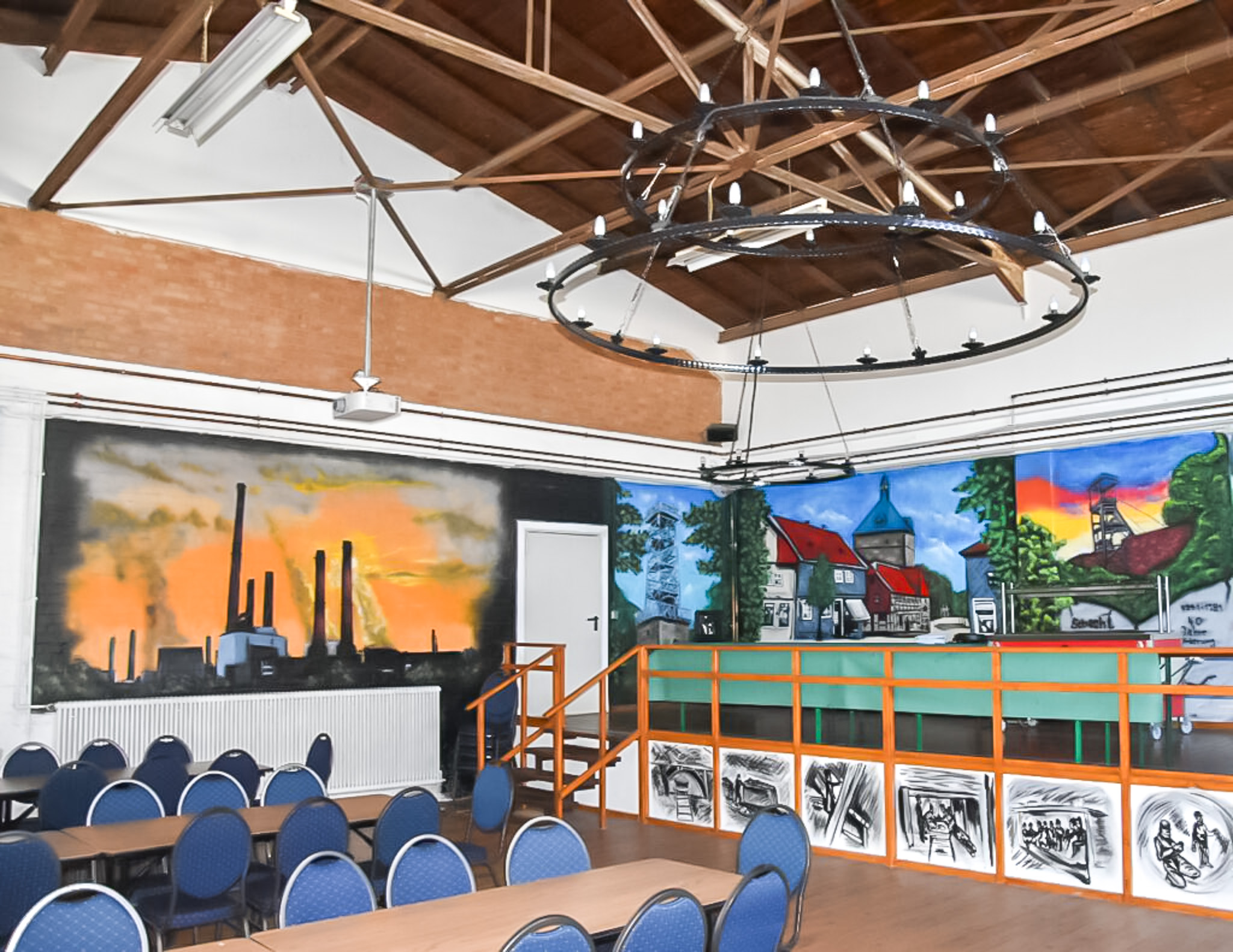 Geräumiger Saal mit industrieller Wandmalerei, Holzdecke und Bühne für Feiern, Tagungen oder Vereinsveranstaltungen.