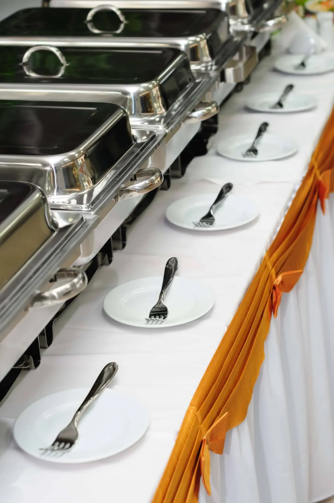Festlich gedecktes Buffet mit Warmhaltebehältern und Tellern, vorbereitet für eine Feier in Leo’s Veranstaltungsräumen Salzgitter.